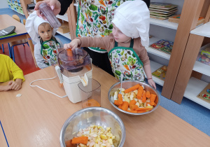 dziewczynka wrzuca marchewkę do sokowirówki